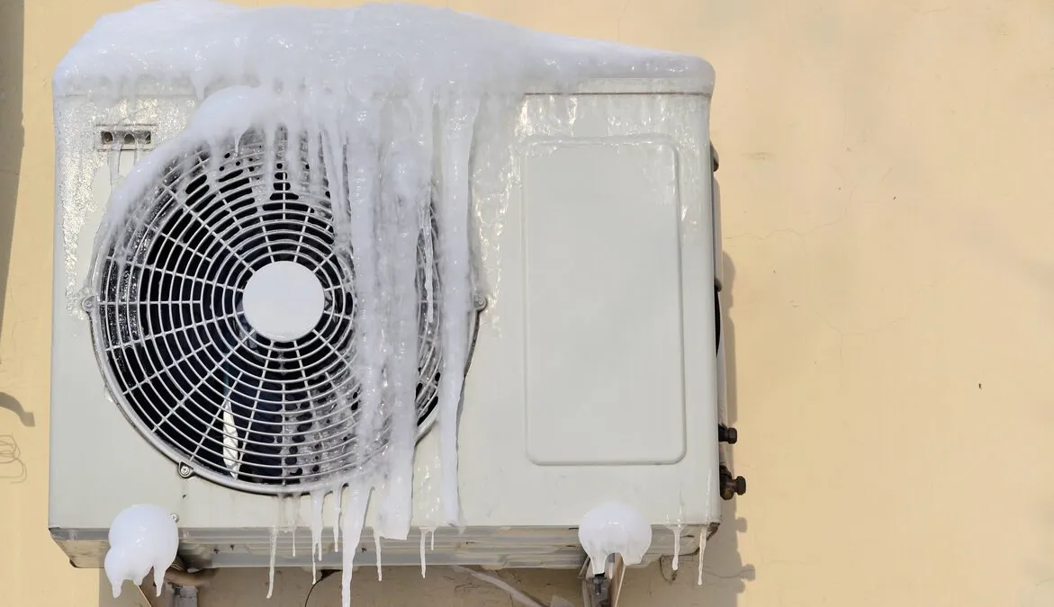 The conditioner covered with icicles on a yellow wall