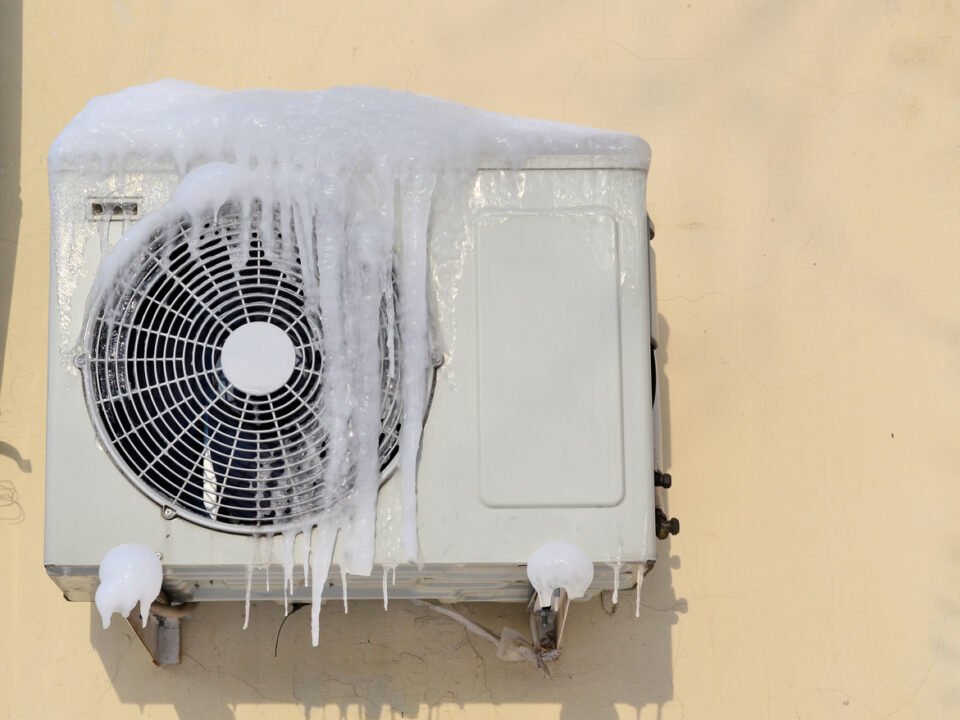 The conditioner covered with icicles on a yellow wall