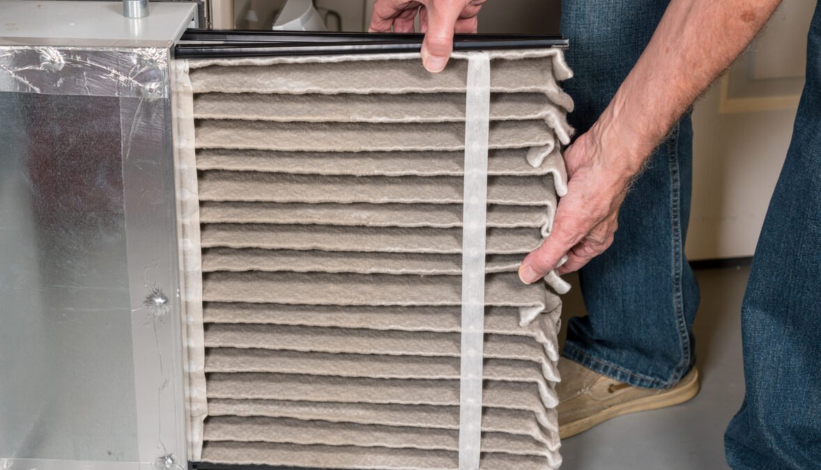 Senior man changing a dirty air filter in a HVAC Furnace