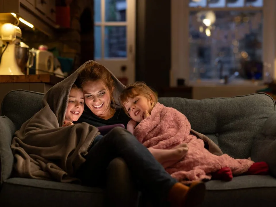 Mom and two daughters warm under blanket